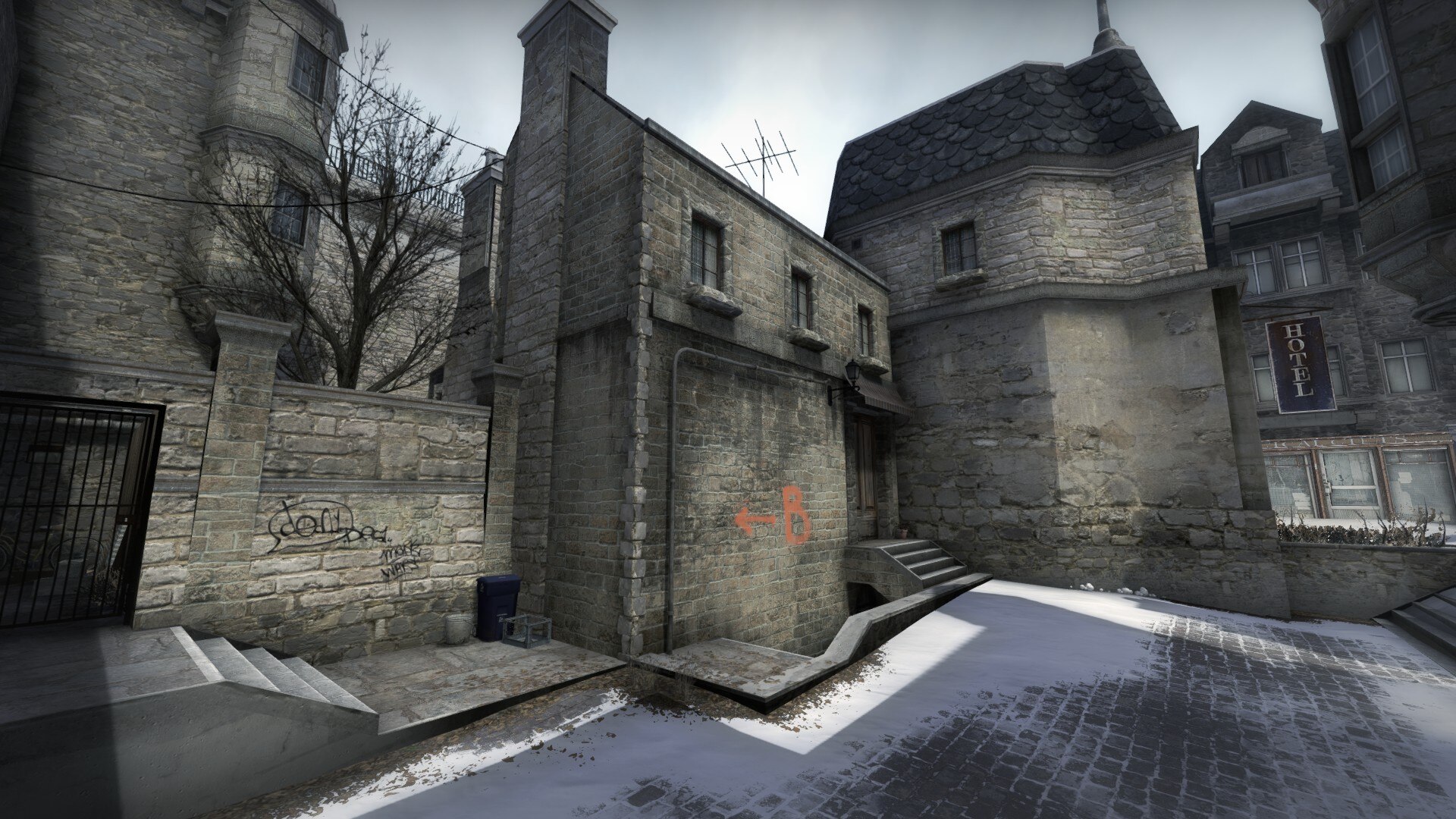 Snowy alley corner with a B arrow painted on the stone wall and a hotel sign above