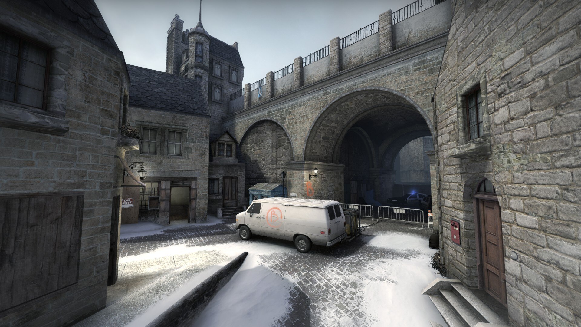 Snowy courtyard with a white van beneath stone arches marking the B site entrance