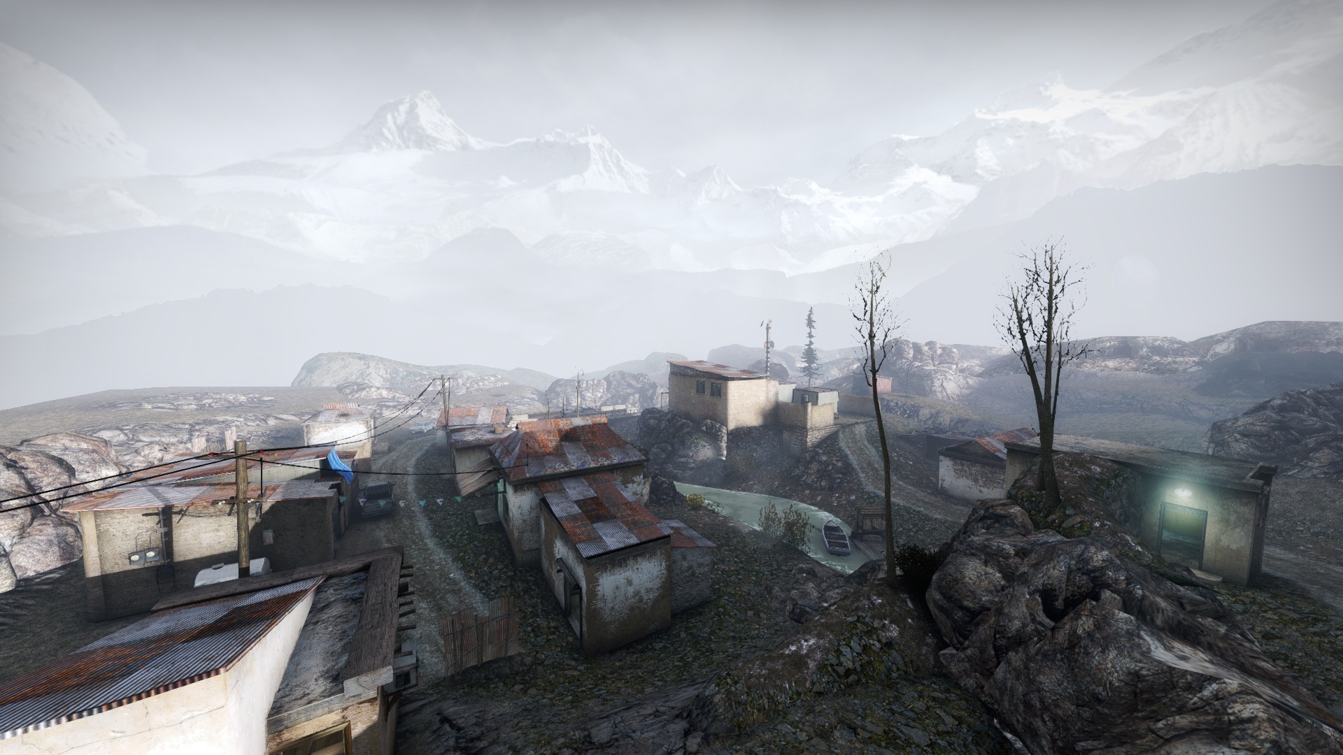 Wide view over misty mountain village rooftops and a river winding between the houses