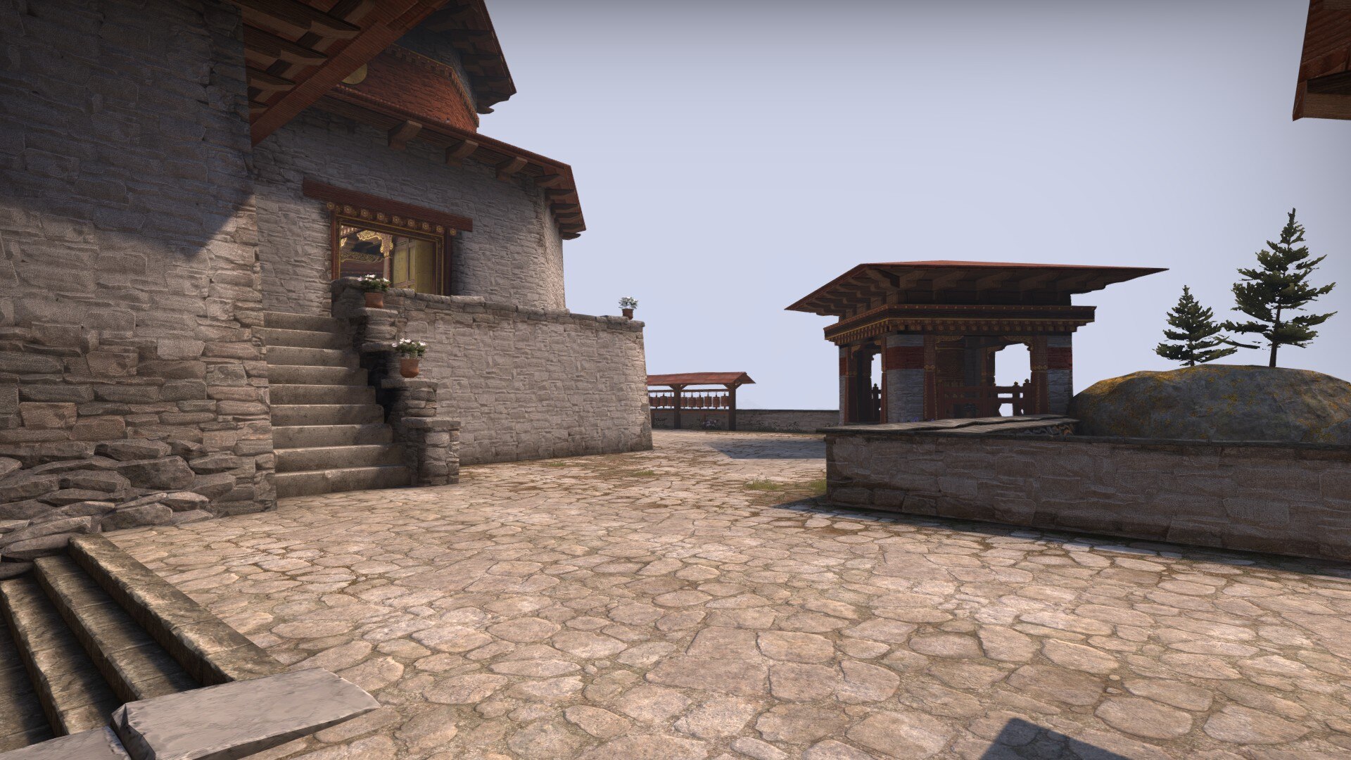 Sunlit courtyard with stone stairs, potted flowers and a pavilion