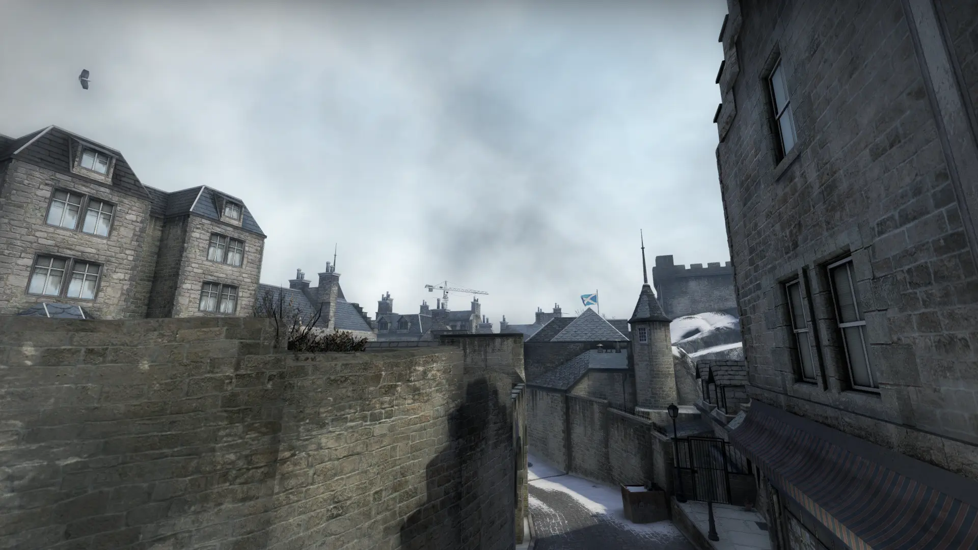 View over a stone wall across rooftops toward a castle tower