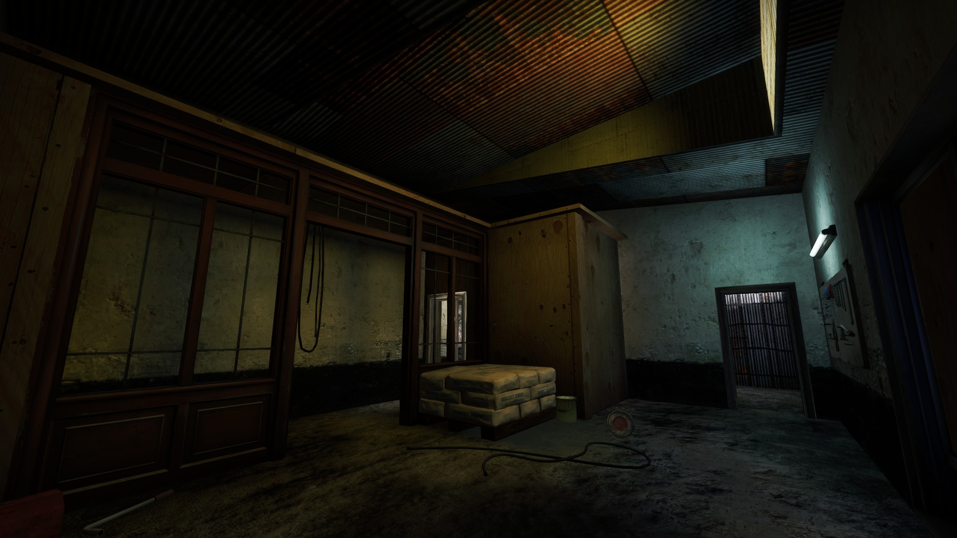Dark interior room with wooden storefront windows, cement sacks and a barred door