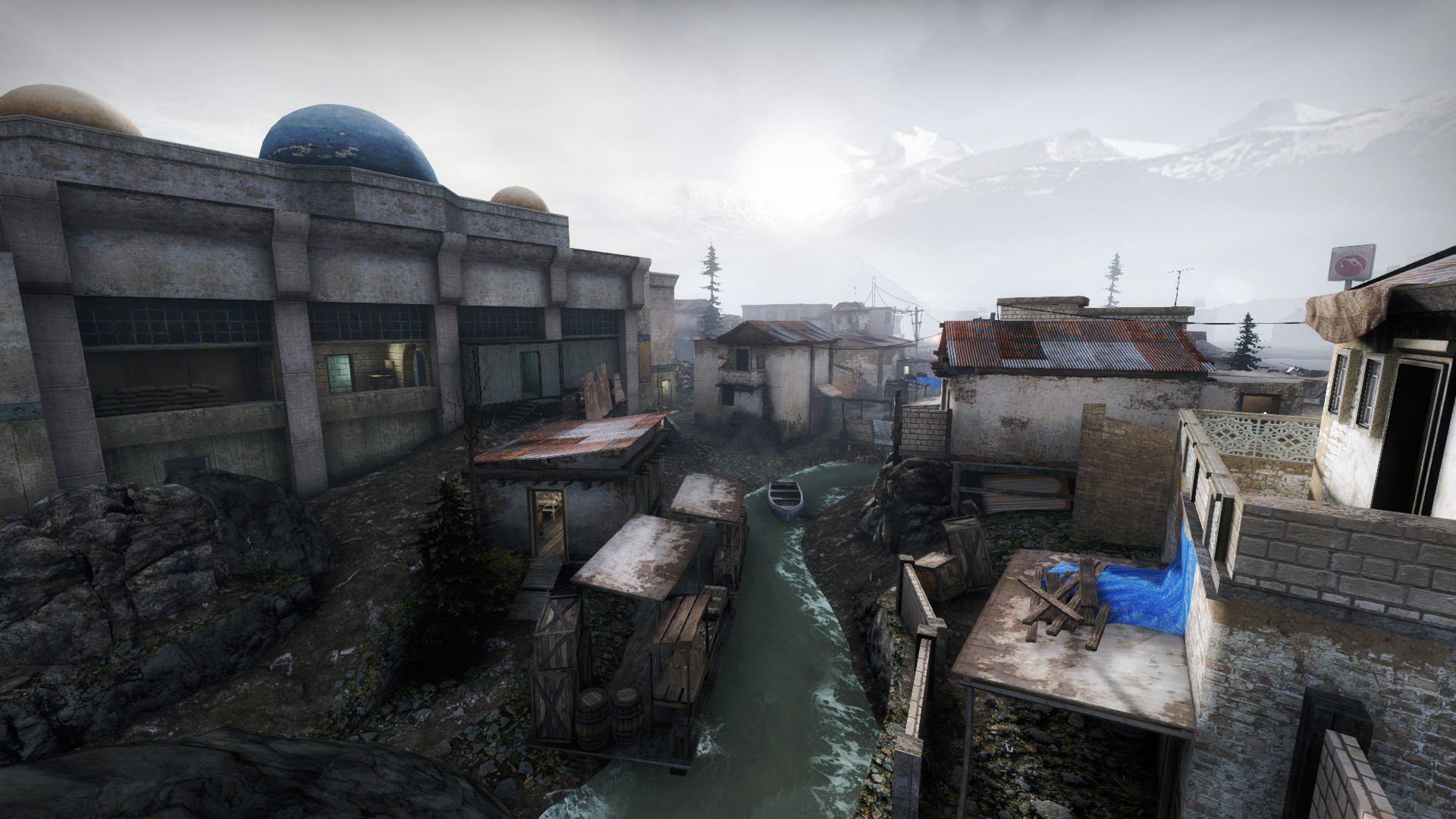 Domed mosque building beside a river with boats and village houses beyond